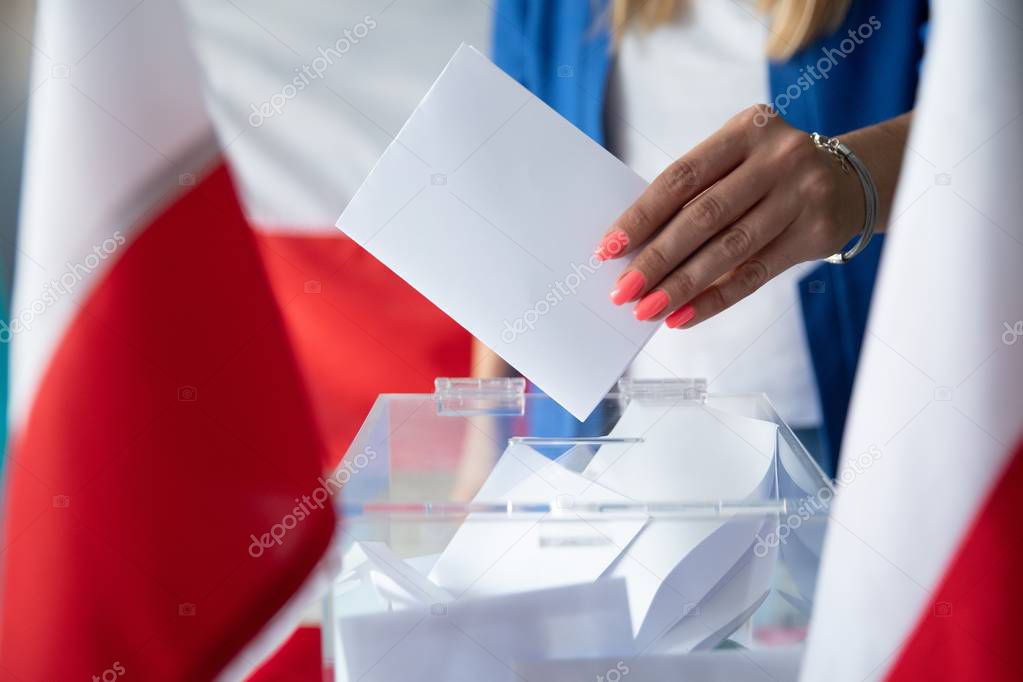 Woman putting her vote to ballot box. Poland political elections