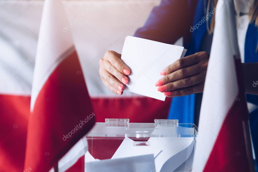 Woman putting her vote to ballot box. Poland political elections