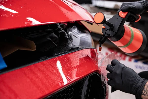 Uomo involucro auto applicando pellicola protettiva trasparente sulla carrozzeria . — Foto Stock