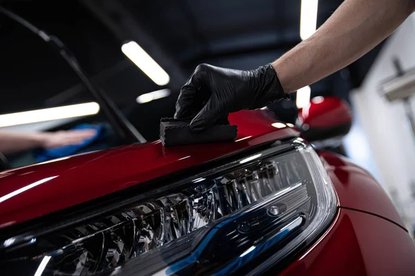 Homem trabalhador de carro detalhando estúdio aplicando revestimento cerâmico em pintura de carro com aplicador de esponja. — Fotografia de Stock