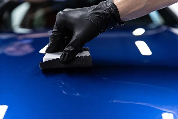 Mann Arbeiter des Auto-Detaillierstudios trägt Keramikbeschichtung auf Autolack mit Schwamm-Applikator auf. — Stockfoto