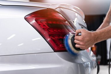 Araba tamircisi. Stüdyonun arka lambasını parlatıyor..