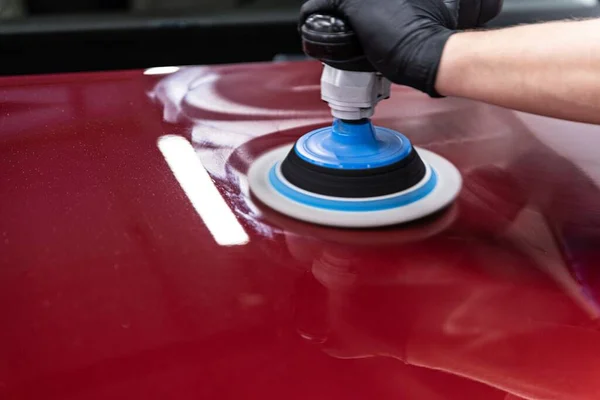 Car detailing studio worker polishing car varnish