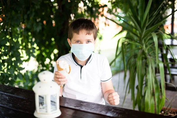 Criança tentando comer sorvete. A usar máscara médica. Criança e covid-19 coronavírus — Fotografia de Stock