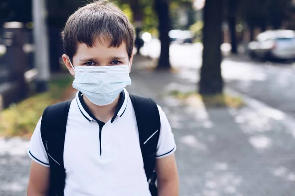 Schuljunge in Maske geht mit Schulrucksack zur Schule. — Stockfoto