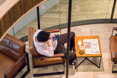 Bangkok, Tayland - 1 Ekim 2018: adam telefonunu danışmanlık kafede. Hemen hemen herkes bir cep telefonu var.