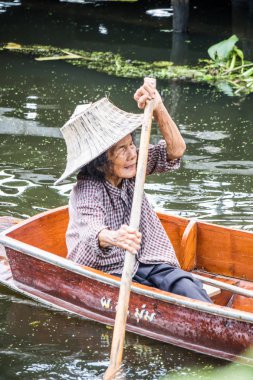 Damnoen Saduak, Tayland - 8 Ekim 2018: bir kadın onun tekne kanal boyunca su bendi kapağı. Yüzen Pazar burada çok popüler bir turistik yer. D