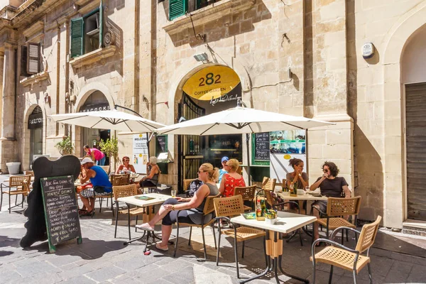 Touristes assis devant un café dans une place — Photo