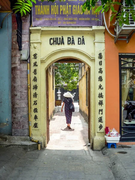 Femme au chapeau conique marchant à travers une porte — Photo