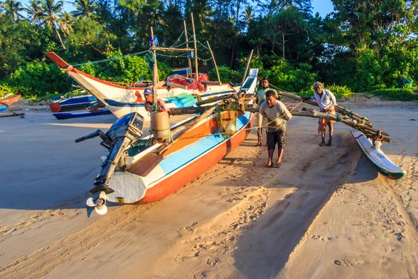 Geleneksel bir balıkçı teknesi taşıyan adamlar kıyıya — Stok fotoğraf