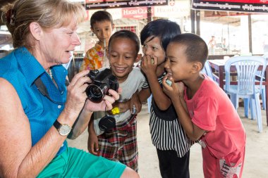 Yangon, Myanmar-5 Mayıs 2014: Bir turist genç Birmanyalı çocuklara fotoğraflarını gösteriyor. Çocuklar yabancılarla tanışmak için meraklı.