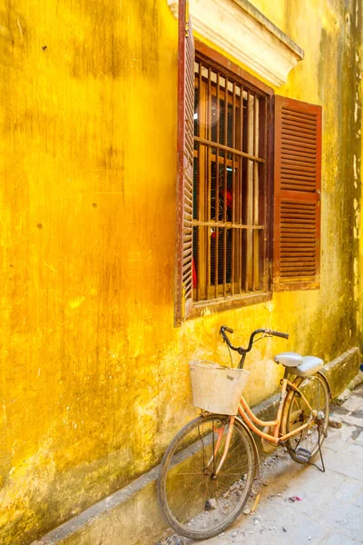 Bicycle leaning up against a yellow wall — Stock Photo, Image