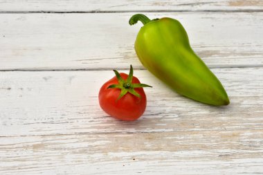 Kırmızı domates ve yeşil dolma biber, ahşap bir masada.