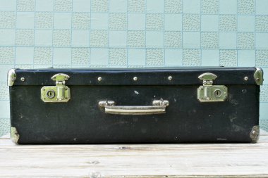 Eski siyah bavul. Masanın üstünde. Kapalı kilitli.