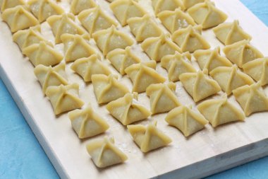 Ahşap kesim tahtasının üzerinde, pişirmeden önce el yapımı manti (Türkçe ravioli tipi hamur tatlısı) 