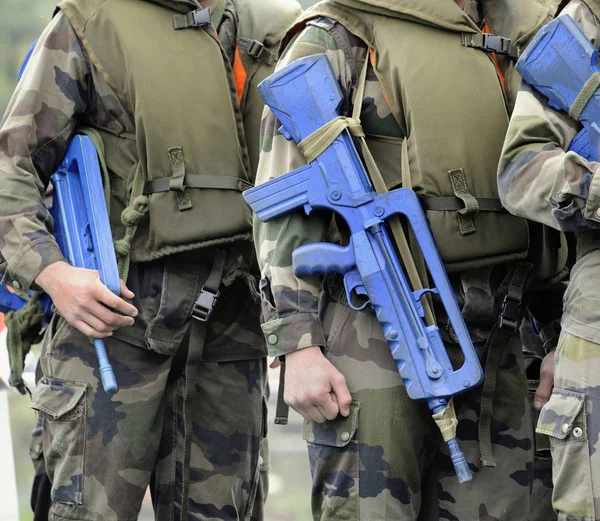 Soldiers in camouflage uniforms and with guns with blue protection against water