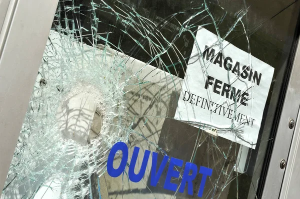 Broken window glass at shop that is closed forever (translation: magasin ferme definitivement means shop closed for ever)