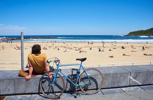 圣塞巴斯蒂安 西班牙 2018年5月11日 一个年轻男子 他们的自行车停放在 Zurriola 海滩前和蒙特卡洛 Ulia 在阳光明媚的日子背景 圣塞巴斯蒂安 — 图库照片
