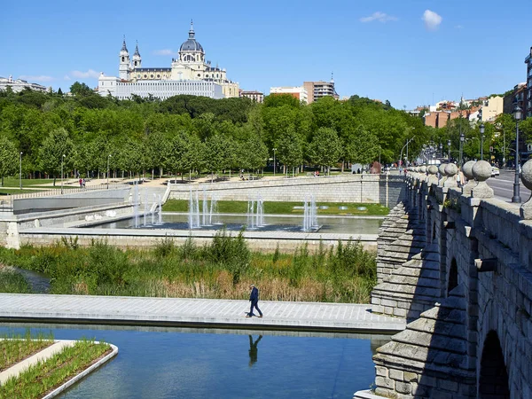 Madrid, İspanya - 15 Mayıs 2018. Puente de Segovia köprü Madrid Rio bahçeleri bahar gün arka plan ve ön planda yürüyen bir erkek Almudena Katedrali ile geçiş. Madrid, İspanya.