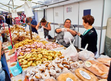 Madrid, Spain - May 15, 2018. Bakers selling Rosquillas del Santo, typical Spanish sweet, in a bakery stall at the San Isidro festivity fair in Pradera de San Isidro park of Madrid. clipart