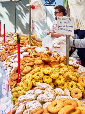 Madrid, Spain - May 15, 2018. Bakers selling Rosquillas del Santo, typical Spanish sweet, in a bakery stall at the San Isidro festivity fair in Pradera de San Isidro park of Madrid. clipart