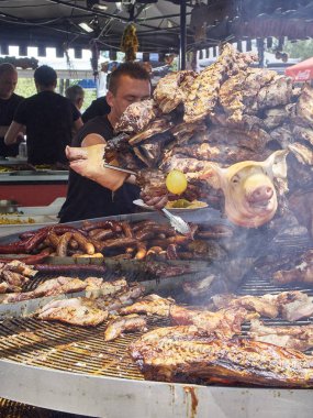 Madrid, İspanya - 15 Mayıs 2018. İspanyol yemek pişirme etler domuz yedek kaburga ve diğerleri kömür Barbekü bir sokak gıda Fuarı bir ahır keser.