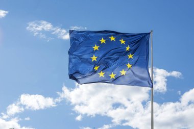 Avrupa Birliği (AB) bayrağı sallayarak üzerinde mavi bir gökyüzü.