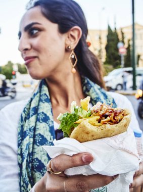 Atina, Yunanistan - 29 Haziran 2018. Pita ekmeği, Yunan sokak gıda tipik ayarla bir geleneksel Gyros yeme Yunan kadın.