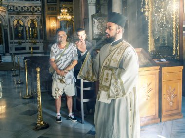 Atina, Yunanistan - 30 Haziran 2018. Ortodoks rahip duyuru, Mitropoli, Atina, Yunanistan ilahi ayini sırasında Büyükşehir katedral kutsal alanlar tapınılıyor için onu bir buhurdan kullanır.