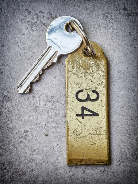Hotel key over a stone background with the key chain number 34.