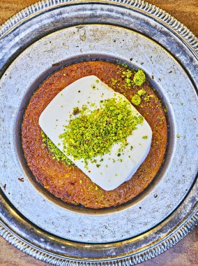 Kunefe, also known as Kenafeh, a traditional Arab dessert made with Kadayif, a thin pastry noodle, soaked in sweet syrup, layered with ice cream and topped with crushed pistachio nuts. clipart