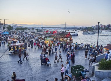 Istanbul, Türkiye - 7 Temmuz 2018. Balık Golden Horn koya bakan Eminönü İskelesi batımında, gelen turist tekneleri ve Haliç Köprüsü arka planda sandviç. Istanbul, Türkiye.