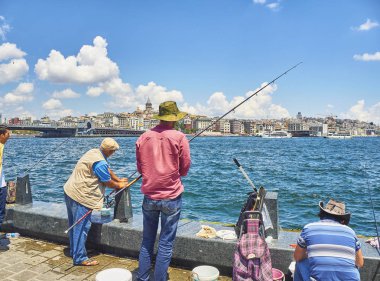 Istanbul, Türkiye - 8 Temmuz 2018. Eminönü İskelesi boğazın ağız Karaköy bölge manzarası içinde belgili tanımlık geçmiş bir görünümü ile karşı karşıya Balık tutma vatandaşlar. Istanbul, Türkiye.