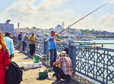 Istanbul, Türkiye - 11 Temmuz 2018. Galata vatandaşlarını Golden Horn Bay ağız ve Eminönü İlçe siluetinin manzarasına balıkçılık ile Süleymaniye Camii içinde belgili tanımlık geçmiş köprü. Istanbul, Türkiye.