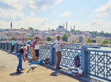 Istanbul, Türkiye - 11 Temmuz 2018. Galata vatandaşlarını Golden Horn Bay ağız ve Eminönü İlçe siluetinin manzarasına balıkçılık ile Süleymaniye Camii içinde belgili tanımlık geçmiş köprü. Istanbul, Türkiye.