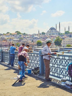 Istanbul, Türkiye - 11 Temmuz 2018. Galata vatandaşlarını Golden Horn Bay ağız ve Eminönü İlçe siluetinin manzarasına balıkçılık ile Süleymaniye Camii içinde belgili tanımlık geçmiş köprü. Istanbul, Türkiye.
