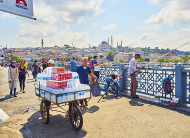 Istanbul, Türkiye - 11 Temmuz 2018. İçecekler ve Eminönü İlçe manzarası ve arka planda Süleymaniye Camii manzaralı Galata Köprüsü'nde balık tutma vatandaşların taşınması teslimatçı. Istanbul, Türkiye.
