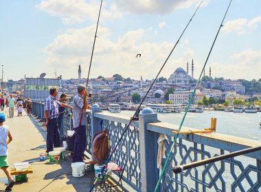 Istanbul, Türkiye - 11 Temmuz 2018. Galata vatandaşlarını Golden Horn Bay ağız ve Eminönü İlçe siluetinin manzarasına balıkçılık ile Süleymaniye Camii içinde belgili tanımlık geçmiş köprü. Istanbul, Türkiye.