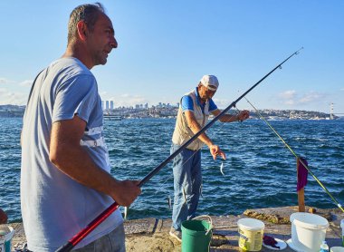 Istanbul, Türkiye - 11 Temmuz 2018. Boğaziçi, Istanbul manzarası içinde belgili tanımlık geçmiş bir görünümü ile Balık tutma vatandaşlar. Türkiye.