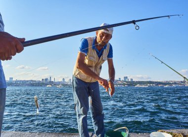 Istanbul, Türkiye - 11 Temmuz 2018. Boğaziçi, Istanbul manzarası içinde belgili tanımlık geçmiş bir görünümü ile Balık tutma vatandaşlar. Türkiye.