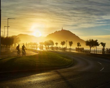The sun sets behind the Monte Urgull of San Sebastian, Basque Country, Guipuzcoa. Spain. View from Zurriola Avenue. clipart