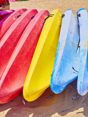 Renkli kayaks kumlu bir plaj üzerinde yığılmış.