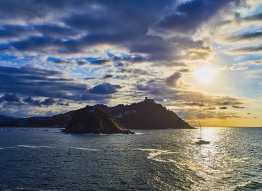 Güneş Santa Clara Adası ve The Monte Igueldo Mount, asıl The Concha Bay unsurları ayarlar. Paseo Nuevo görünümden. San Sebastian, Donostia, Bask Ülkesi, Guipuzcoa. İspanya.