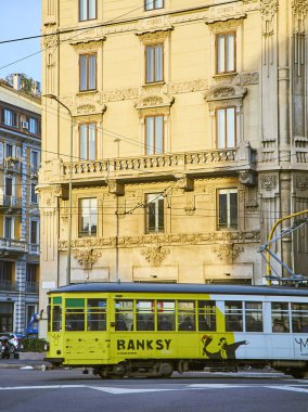 A tram advertising a monographic exhibition of Banksy crossing Via Giovanni Boccaccio. Milan, Lombardy, Italy. clipart