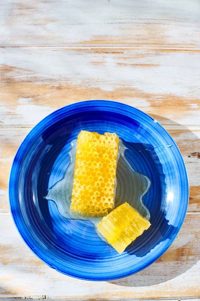 Pièce en nid d'abeille avec du miel sur une assiette bleue . — Photo