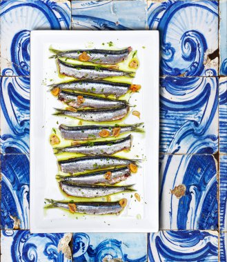 Anchovies cooked Basque Country style over a tiled background. clipart