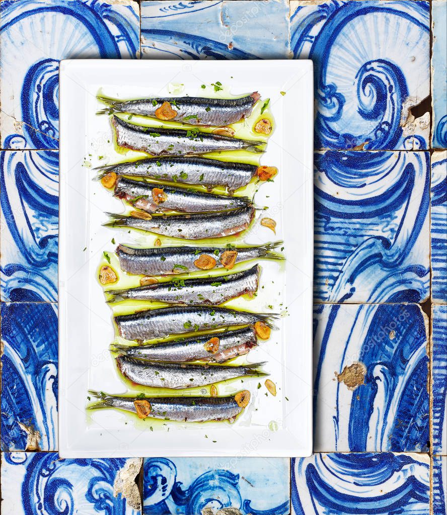 Anchovies cooked Basque Country style over a tiled background.