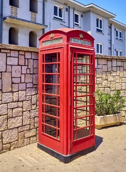 A red telephone box in a street.