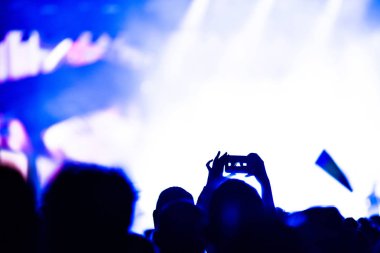 Dokunmatik akıllı telefon fotoğraflarla bir müzik konser sırasında alan insanlar. Parlak sahne ışıkları