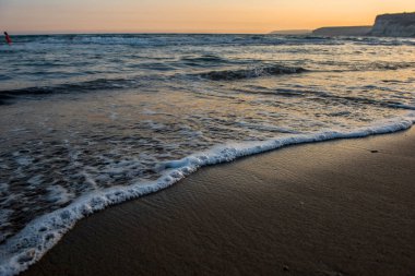 Kumlu plaj altın günbatımı sırasında yaklaşan dalgalar
